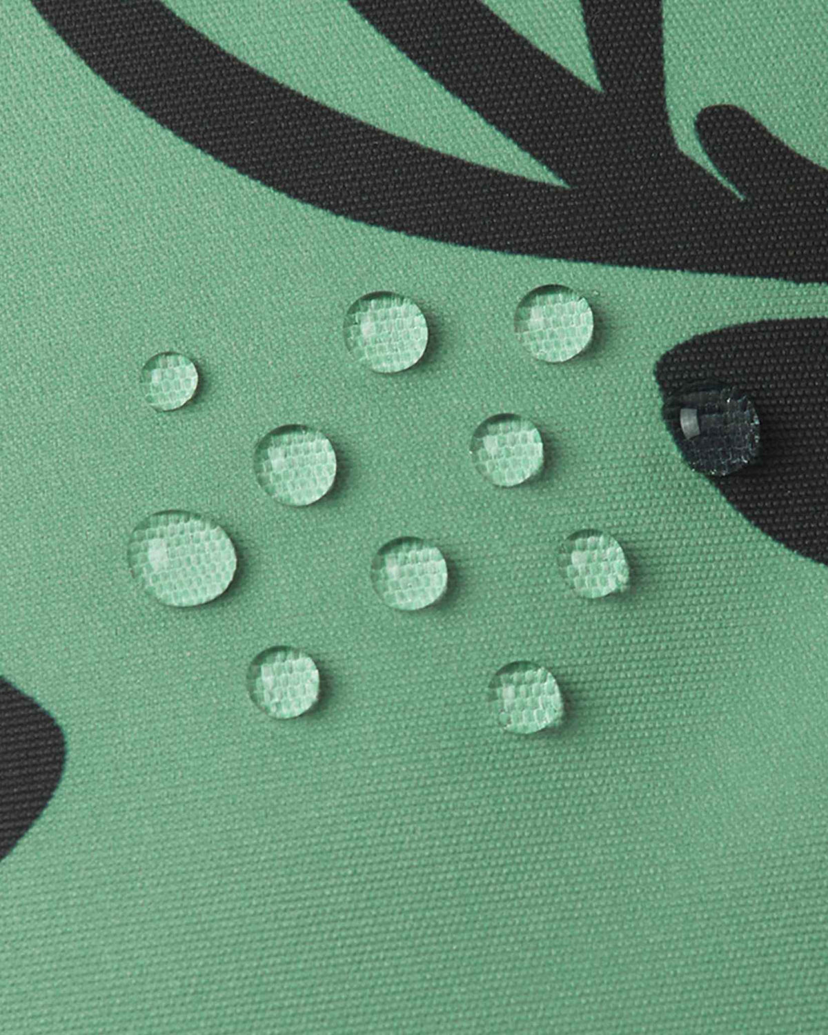 Close-up of water droplets beading on the green clay Reima Kurikka fabric, demonstrating its waterproof and dirt-repellent surface.
