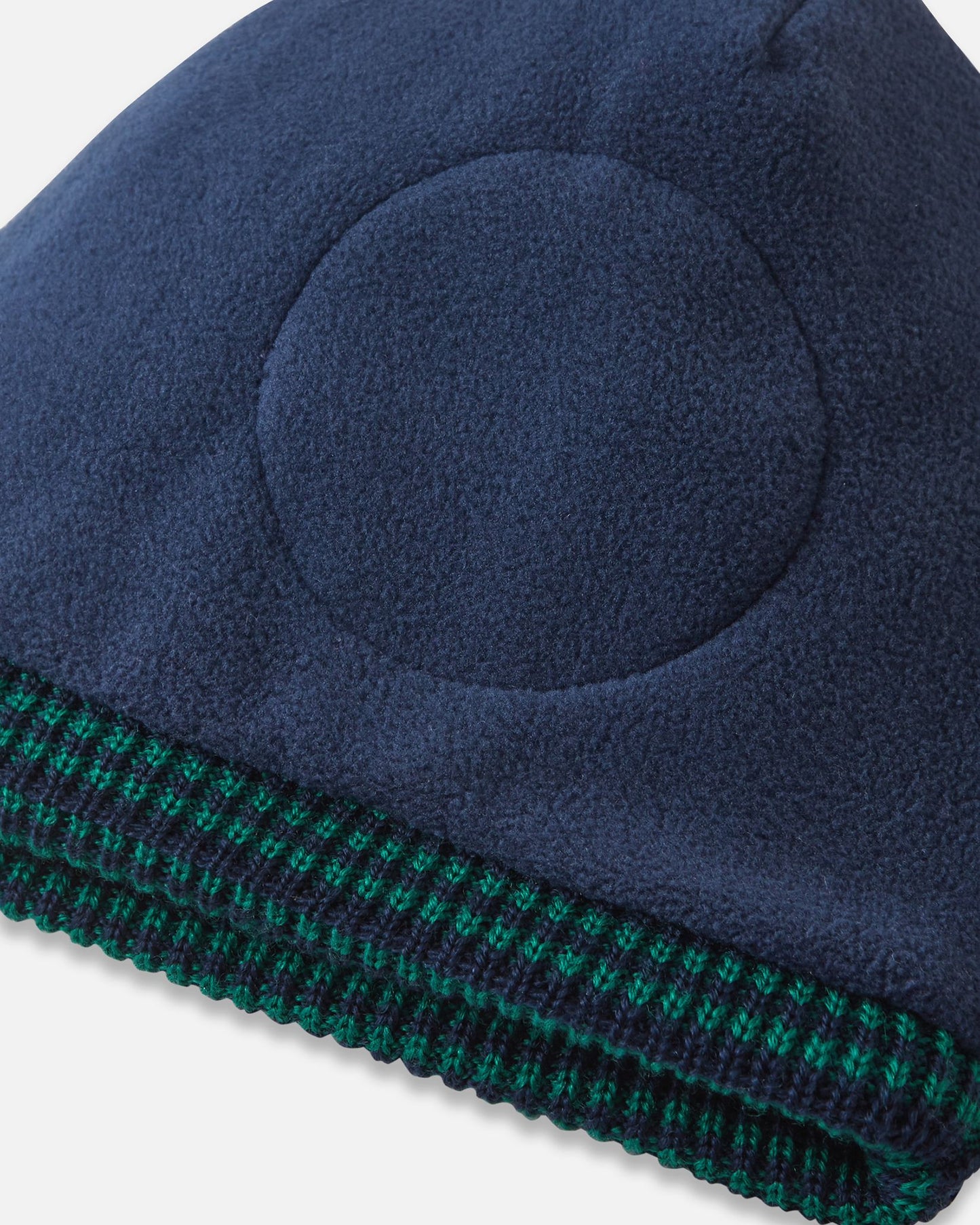Close-up inside detail of the navy blue Reima Kuurassa kids' wool beanie, showing the soft fleece inner lining and the built-in circular windproof earpieces designed to protect little ears from harsh winter winds.
