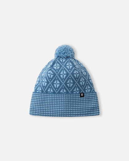 Front view of the Reima Kuurassa kids' merino wool beanie hat in ocean blue, featuring a Nordic-inspired geometric pattern, a ribbed fold-over brim, and a matching pom-pom.