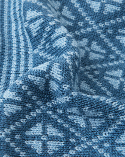 Macro close-up of the premium knitted merino wool texture on the ocean blue Reima Kuurassa kids' beanie, demonstrating the intricate Nordic pattern and the soft, temperature-regulating winter yarn.