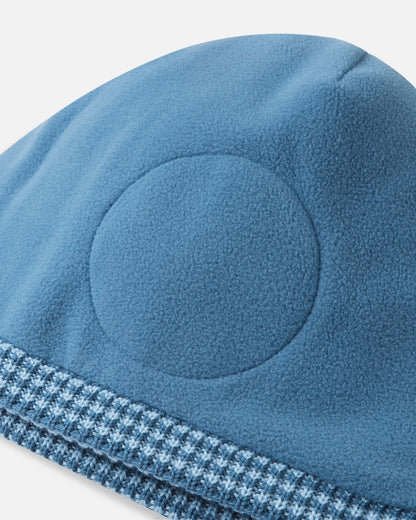 Close-up inside detail of the ocean blue Reima Kuurassa kids' wool beanie, showing the soft fleece inner lining and the built-in circular windproof earpieces designed for extra winter protection.