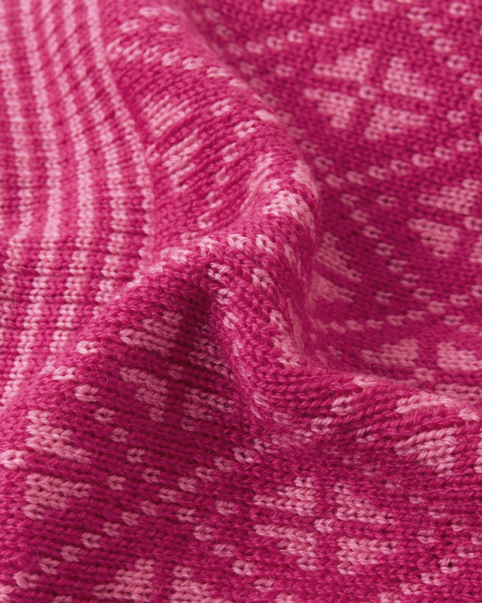 Macro close-up of the premium knitted merino wool texture on the rosy berry Reima Kuurassa kids' beanie, demonstrating the intricate Nordic pattern and the soft, temperature-regulating winter yarn.