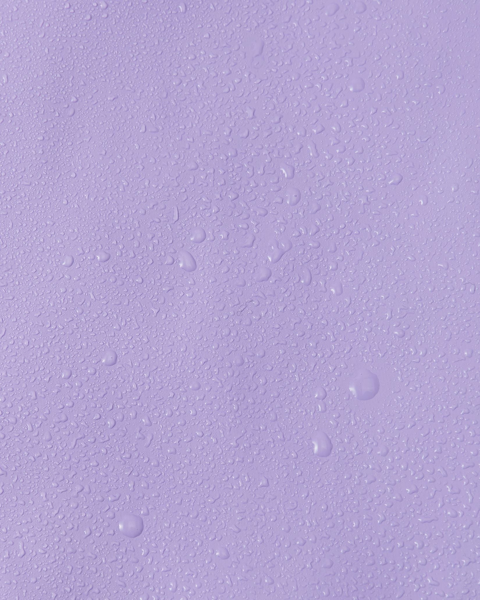Close-up macro shot showing water droplets tightly beading on the smooth, waterproof polyurethane surface of the Reima Lampi blooming lilac raincoat, demonstrating its superior ability to repel water and keep children completely dry during heavy rain.
