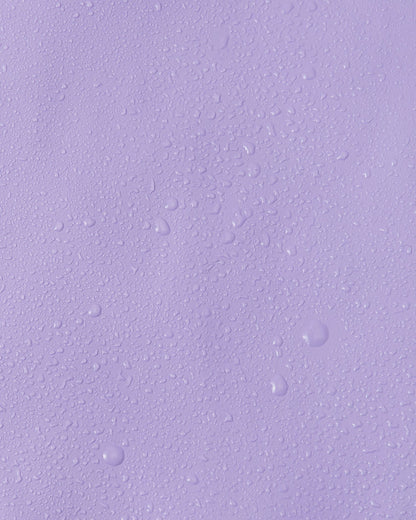 Close-up macro shot showing water droplets tightly beading on the smooth, waterproof polyurethane surface of the Reima Lampi blooming lilac raincoat, demonstrating its superior ability to repel water and keep children completely dry during heavy rain.