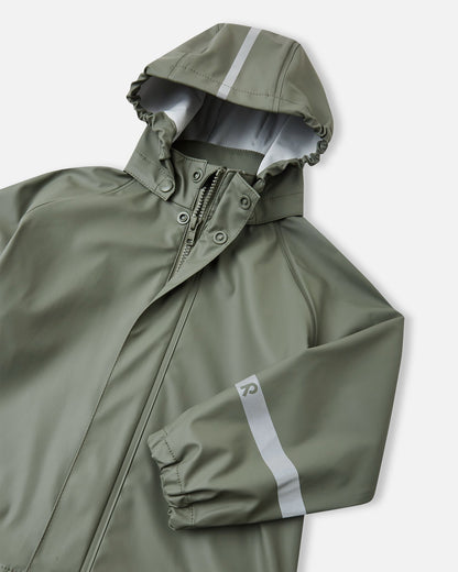 Detailed angled front view of the Reima Lampi greyish-green raincoat, showcasing the smooth-running front zipper, an elasticized hood designed to stay up in windy weather, and a prominent high-visibility reflective stripe centered on the hood.