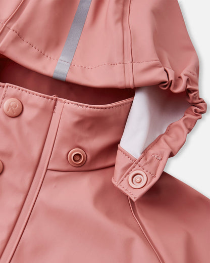Detailed close-up of the Reima Lampi raincoat collar in rose blush, highlighting the child-safe snap button attachments that allow the hood to detach quickly and safely if it accidentally gets snagged on tree branches during outdoor play.