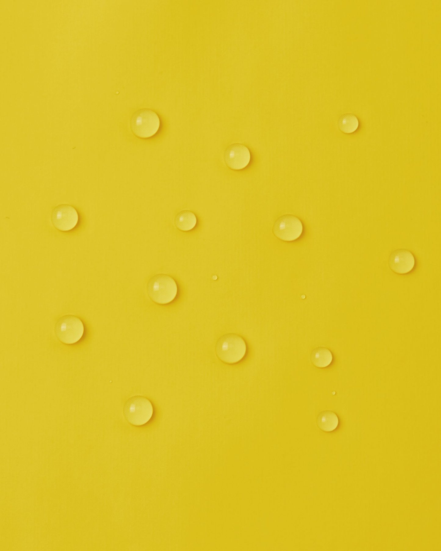 Macro close-up of water droplets perfectly beading on the smooth, bright yellow waterproof polyurethane surface of the Reima Lampi raincoat, demonstrating its excellent ability to repel rain and keep kids completely dry.
