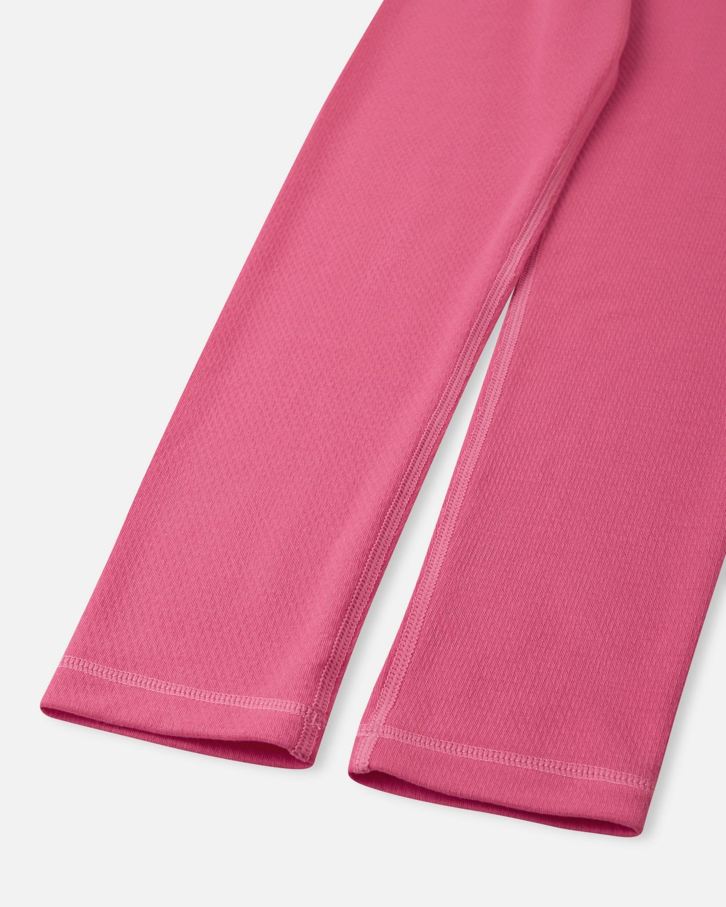 Close-up of the ankle cuffs and durable flatlock stitching on the soft coral Reima Lani kids' thermal base layer leggings.