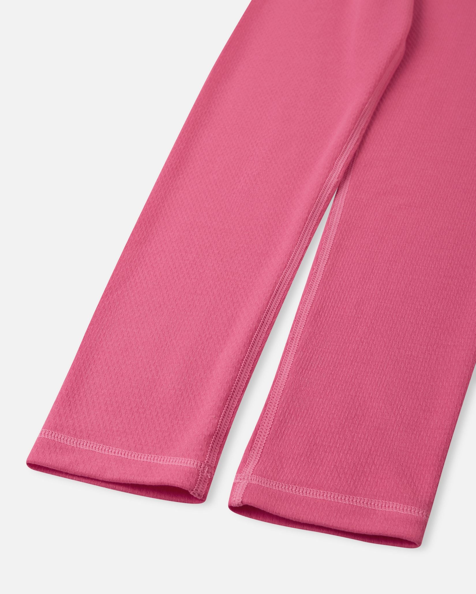 Close-up of the ankle cuffs and durable flatlock stitching on the soft coral Reima Lani kids' thermal base layer leggings.