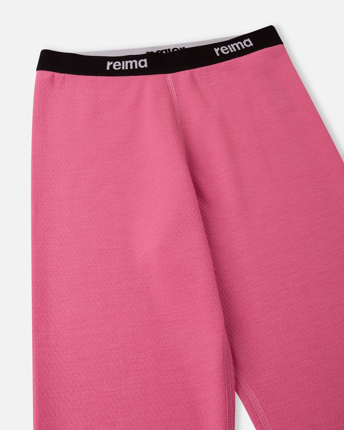Detailed close-up of the soft elastic waistband with the Reima logo on the soft coral Lani kids' thermal base layer pants.