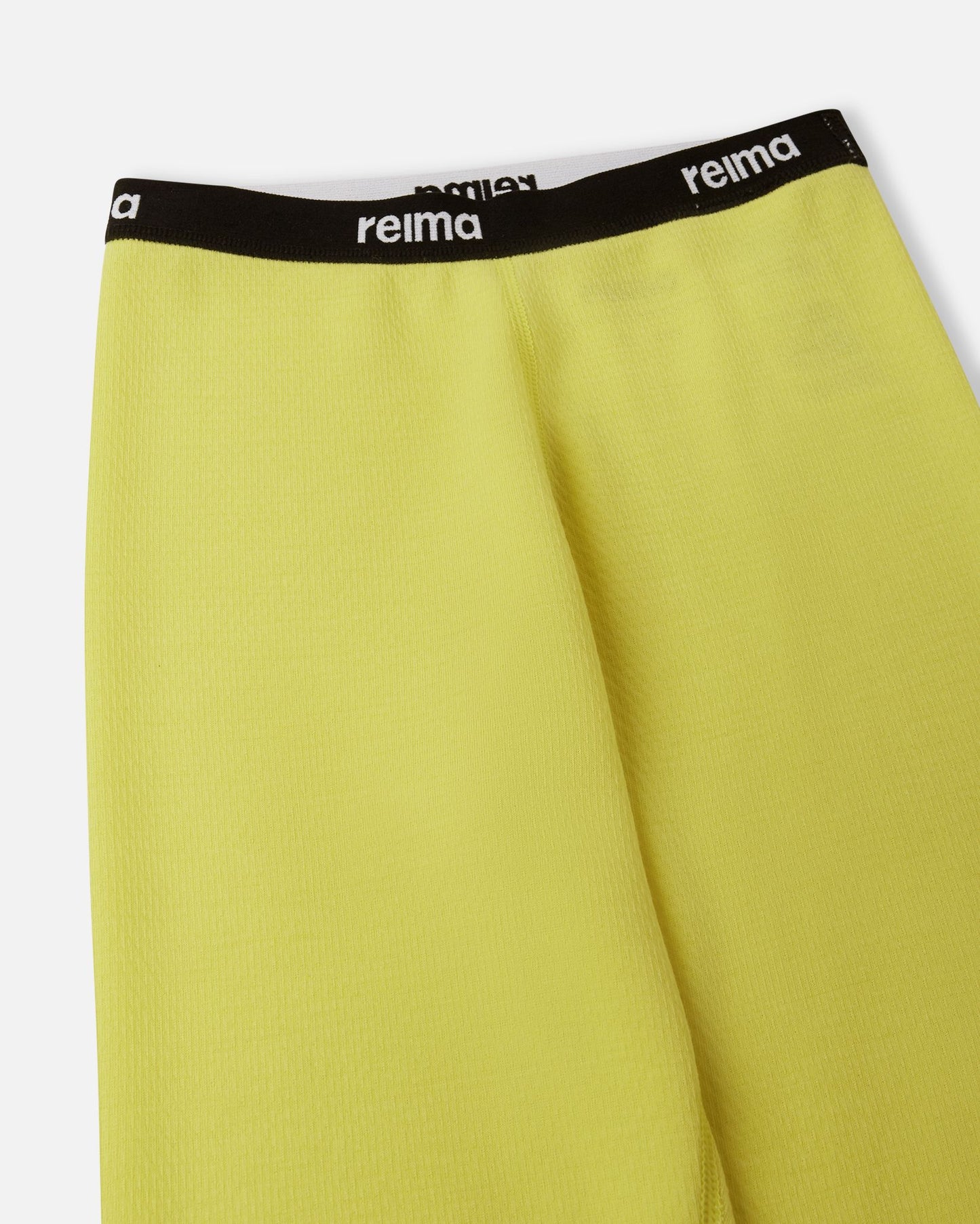 Detailed close-up of the soft elastic waistband featuring the Reima logo on the yellow Lani kids' thermal base layer pants.