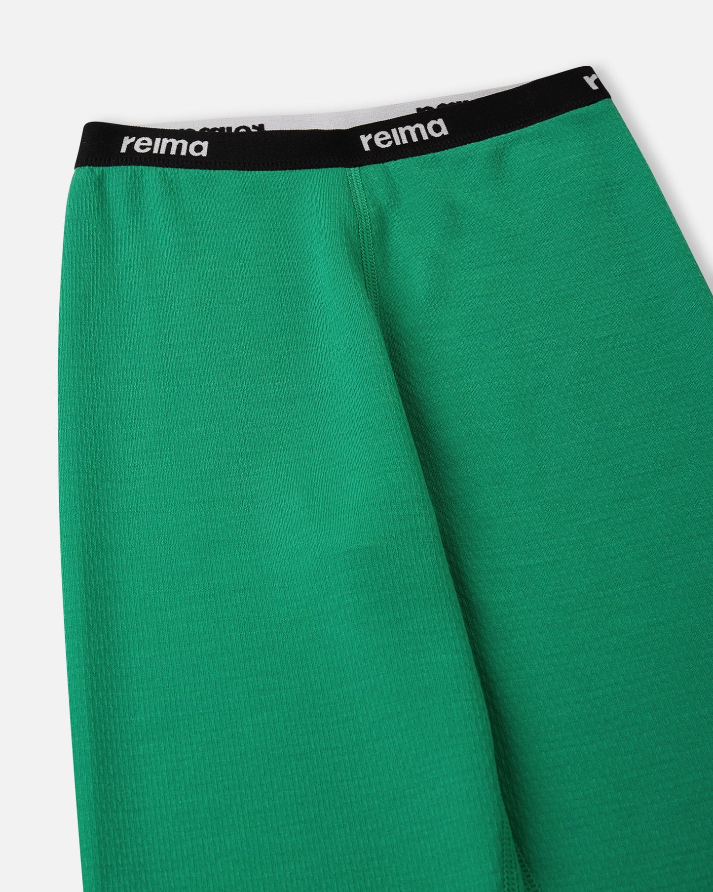 Detailed view of the soft elastic waistband featuring the Reima logo on the green Lani kids' thermal base layer bottoms.