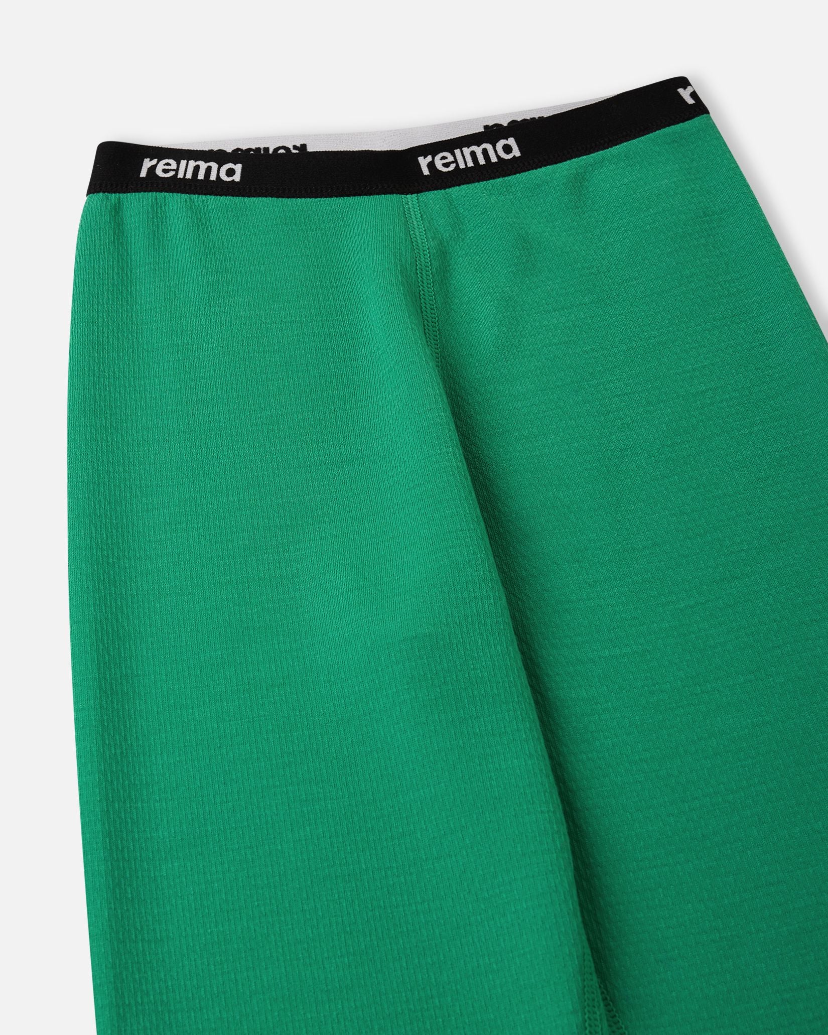 Detailed view of the soft elastic waistband featuring the Reima logo on the green Lani kids' thermal base layer bottoms.