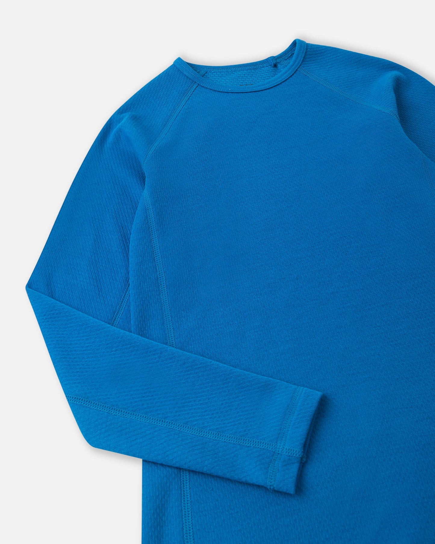 Close-up detail of the crew neck collar and raglan sleeve stitching on the bright blue Reima Lani kids' moisture-wicking thermal shirt.