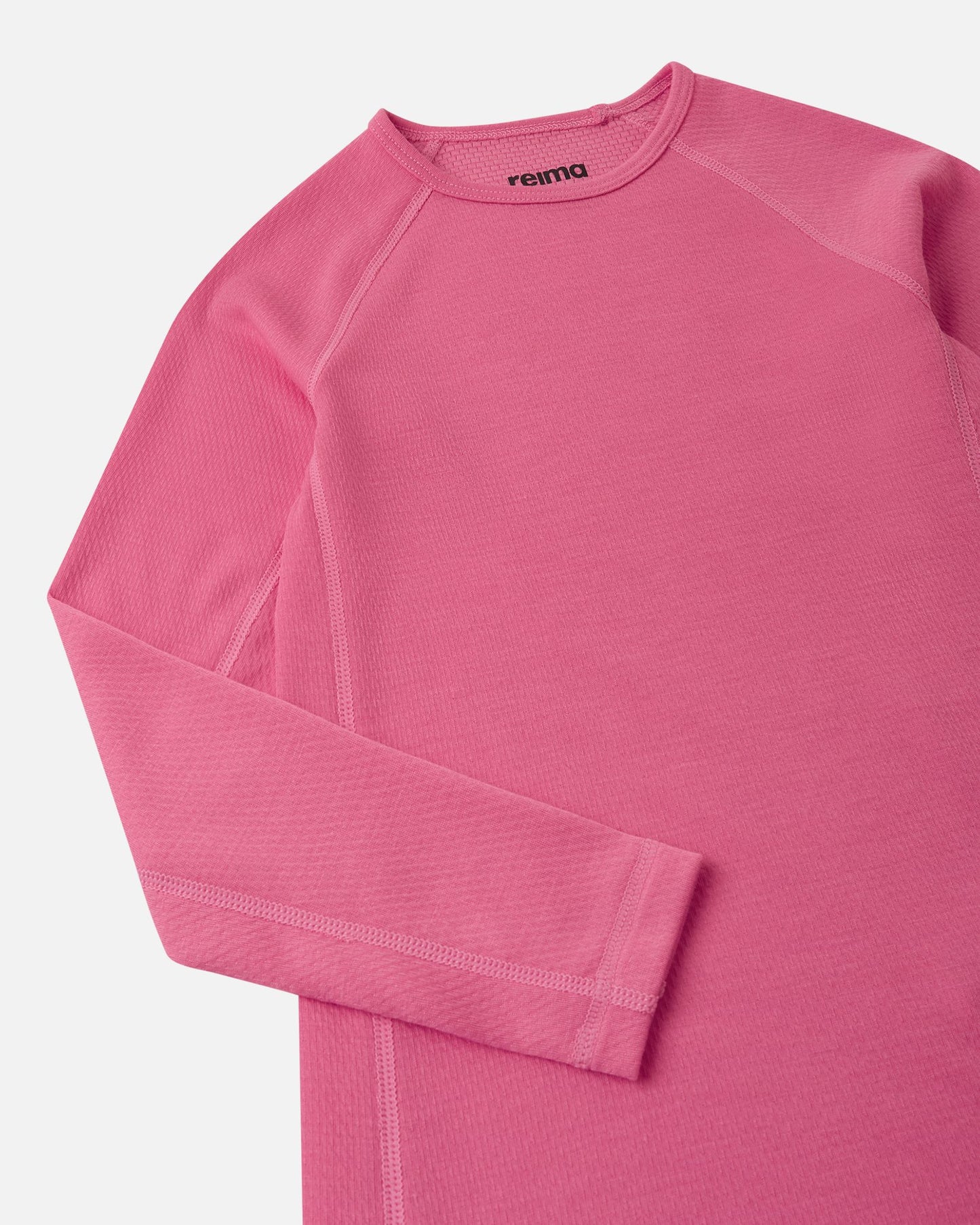 Close-up of the crew neck collar and raglan sleeve construction on the soft coral Reima Lani kids' moisture-wicking thermal top.