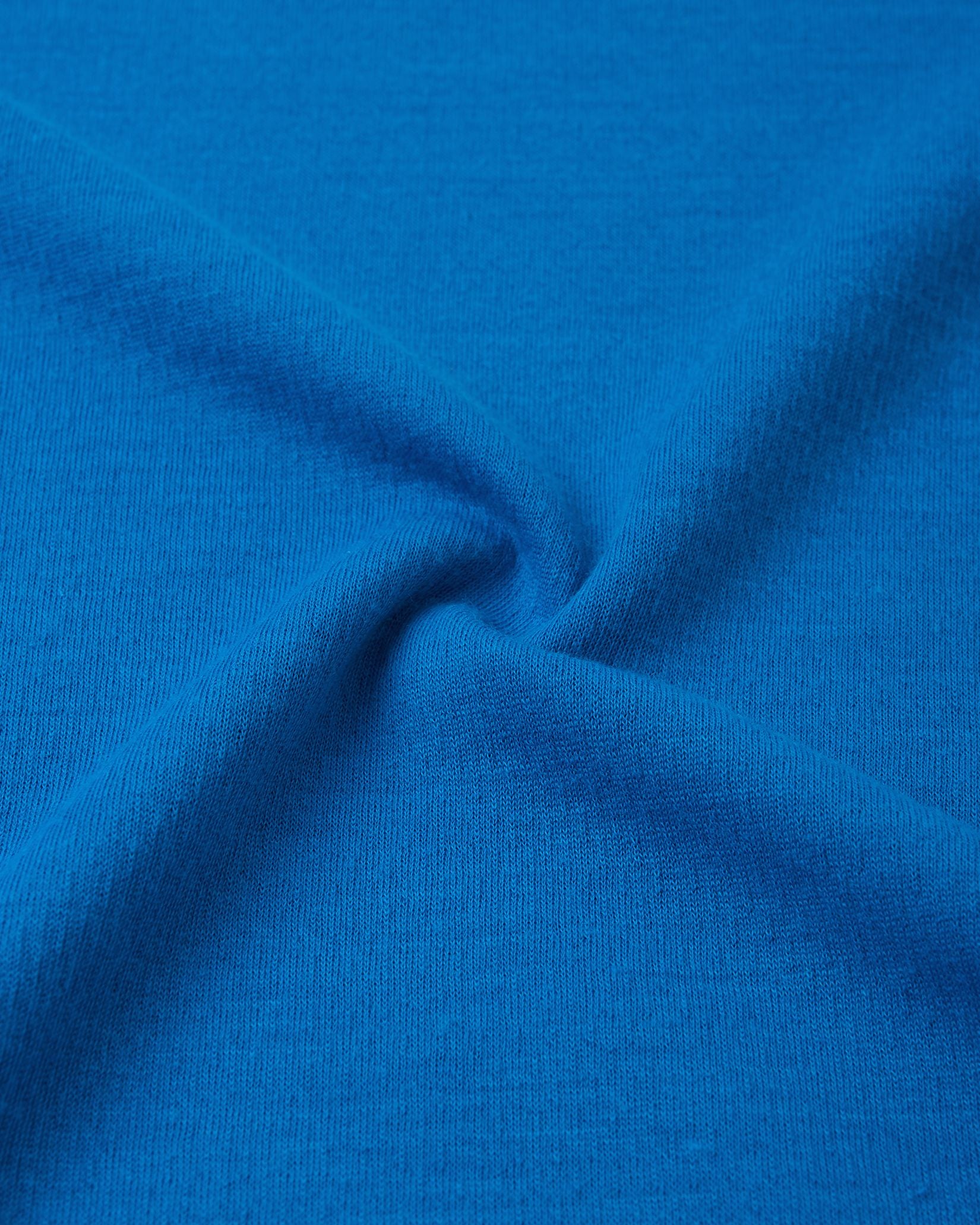 Macro close-up of the technical knit fabric on the bright blue Reima Lani kids' Thermolite base layer, highlighting its moisture-wicking grid texture.
