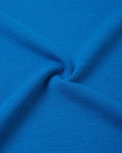 Macro close-up of the technical knit fabric on the bright blue Reima Lani kids' Thermolite base layer, highlighting its moisture-wicking grid texture.