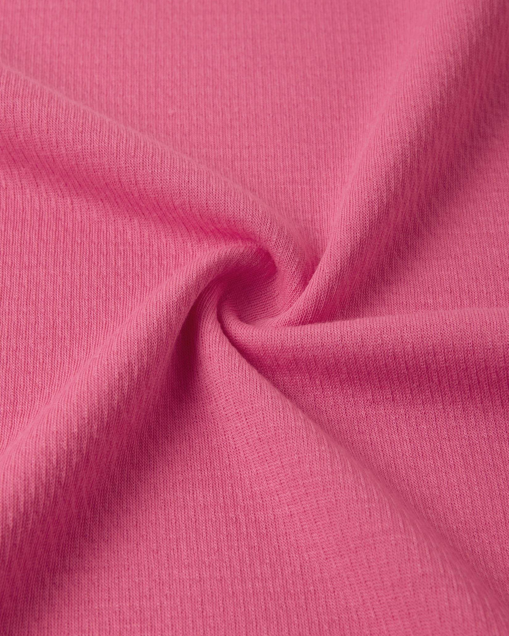 Macro close-up of the technical knit fabric on the soft coral Reima Lani kids' Thermolite base layer, showing the specialized moisture-wicking grid structure.