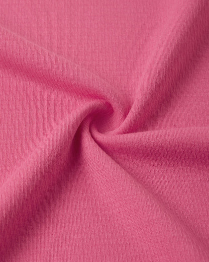 Macro close-up of the technical knit fabric on the soft coral Reima Lani kids' Thermolite base layer, showing the specialized moisture-wicking grid structure.