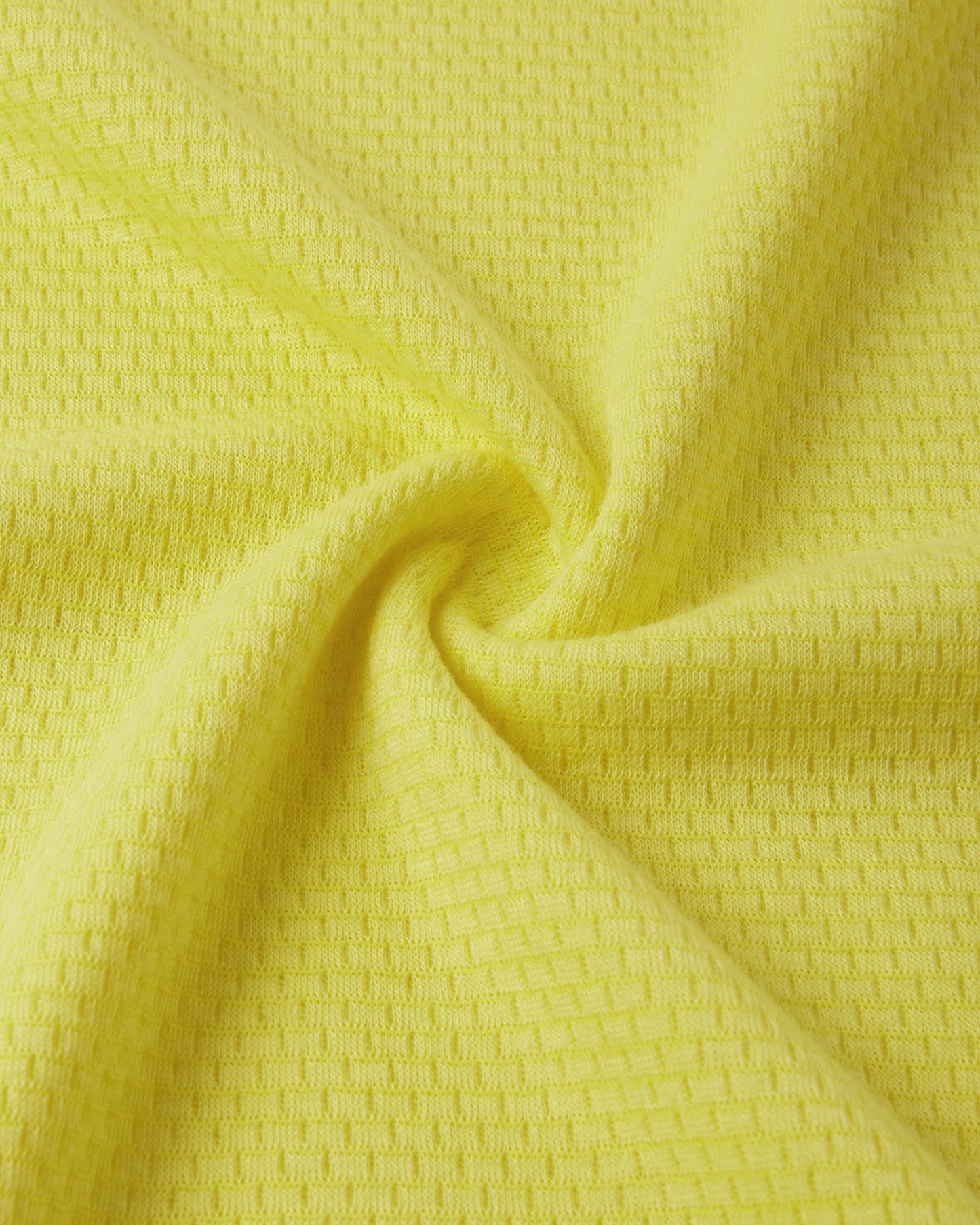 Macro close-up of the technical knit fabric on the yellow Reima Lani kids' Thermolite base layer, showing the specialized moisture-wicking grid structure.