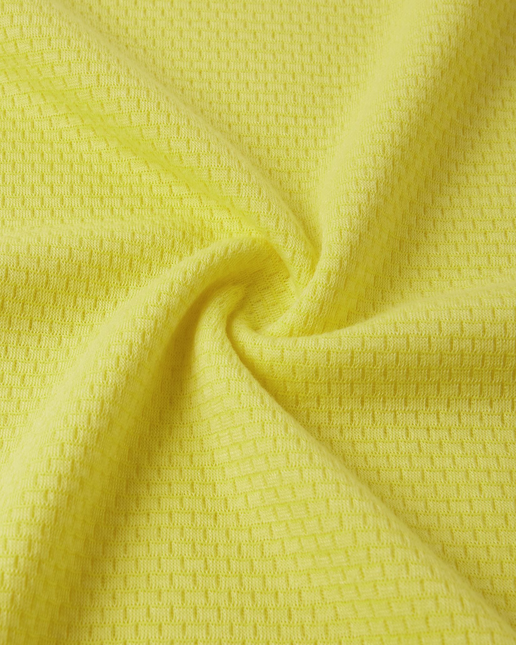 Macro close-up of the technical knit fabric on the yellow Reima Lani kids' Thermolite base layer, showing the specialized moisture-wicking grid structure.