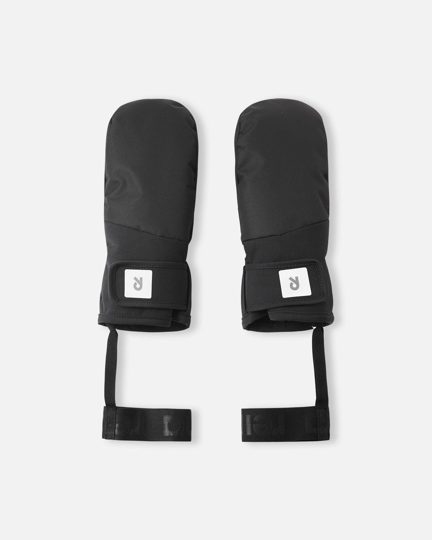 Flat lay view of the backs of the all-black Reima Lapases kids' ski mittens, highlighting the durable waterproof ReimaTec fabric, adjustable hook-and-loop wrist straps for a secure fit, and attached elastic safety wrist leashes.