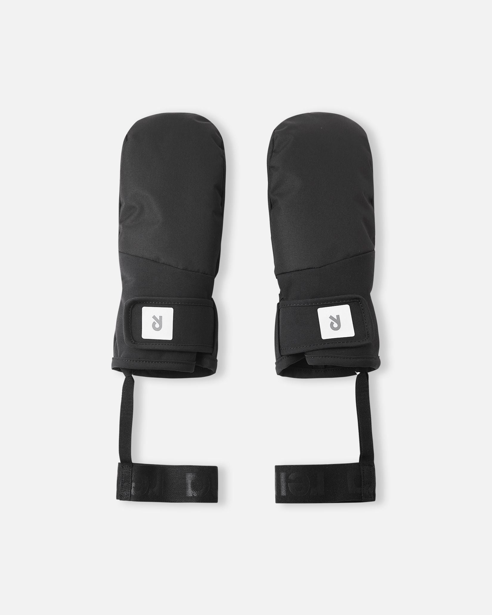 Flat lay view of the backs of the all-black Reima Lapases kids' ski mittens, highlighting the durable waterproof ReimaTec fabric, adjustable hook-and-loop wrist straps for a secure fit, and attached elastic safety wrist leashes.