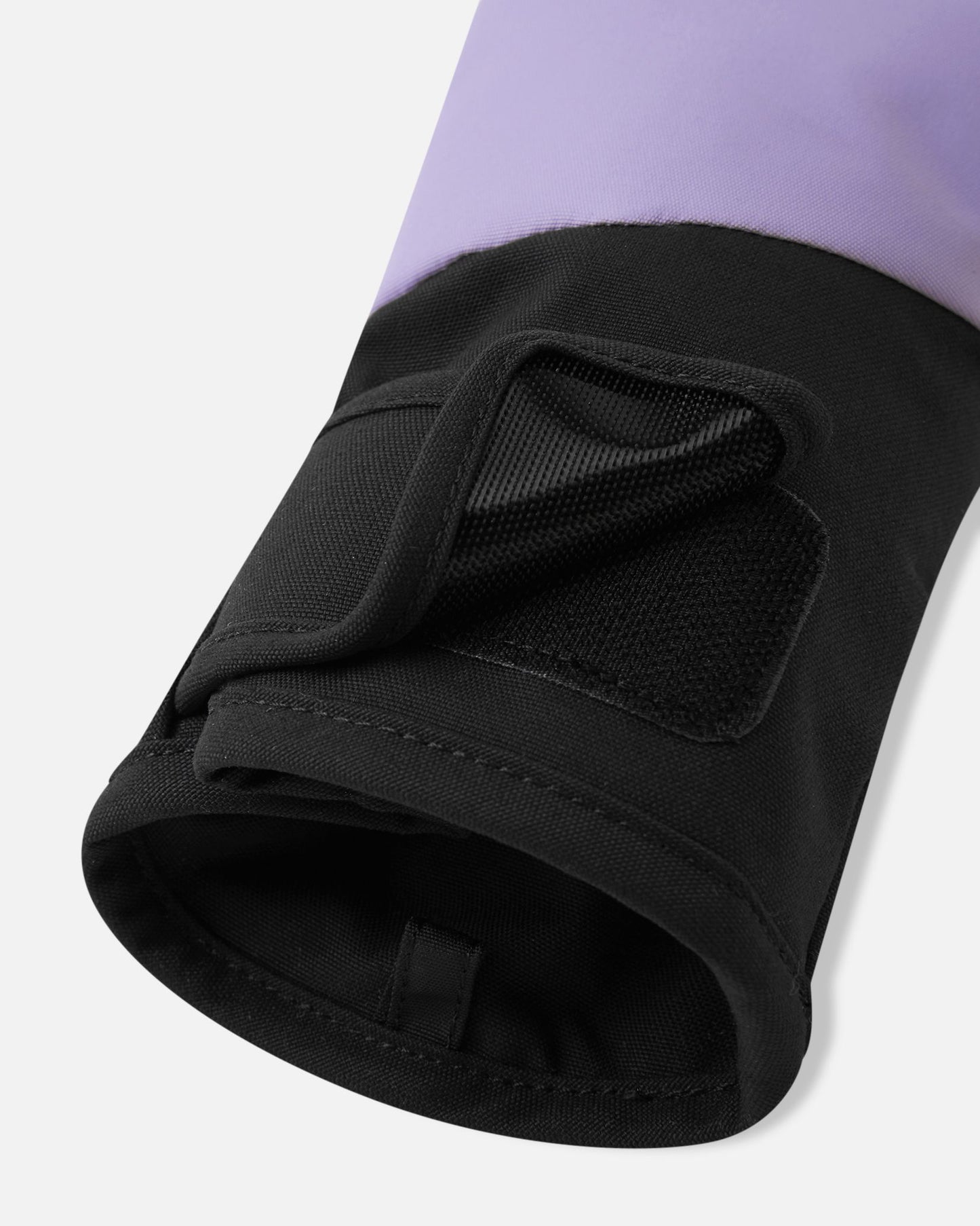 Close-up detail of the cuff on the blooming lilac Reima Lapases kids' ski mittens. The image highlights the adjustable hook-and-loop tab closure and the black elastic safety wrist leash designed to prevent accidental loss on the slopes.