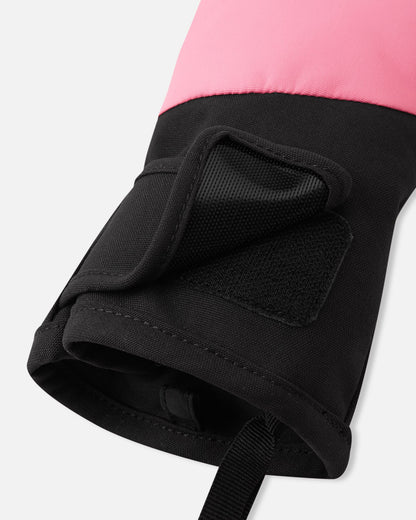 Close-up detail of the cuff on the soft coral Reima Lapases kids' ski mittens, highlighting the adjustable hook-and-loop tab closure and the black elastic safety wrist leash designed to prevent dropped gear.