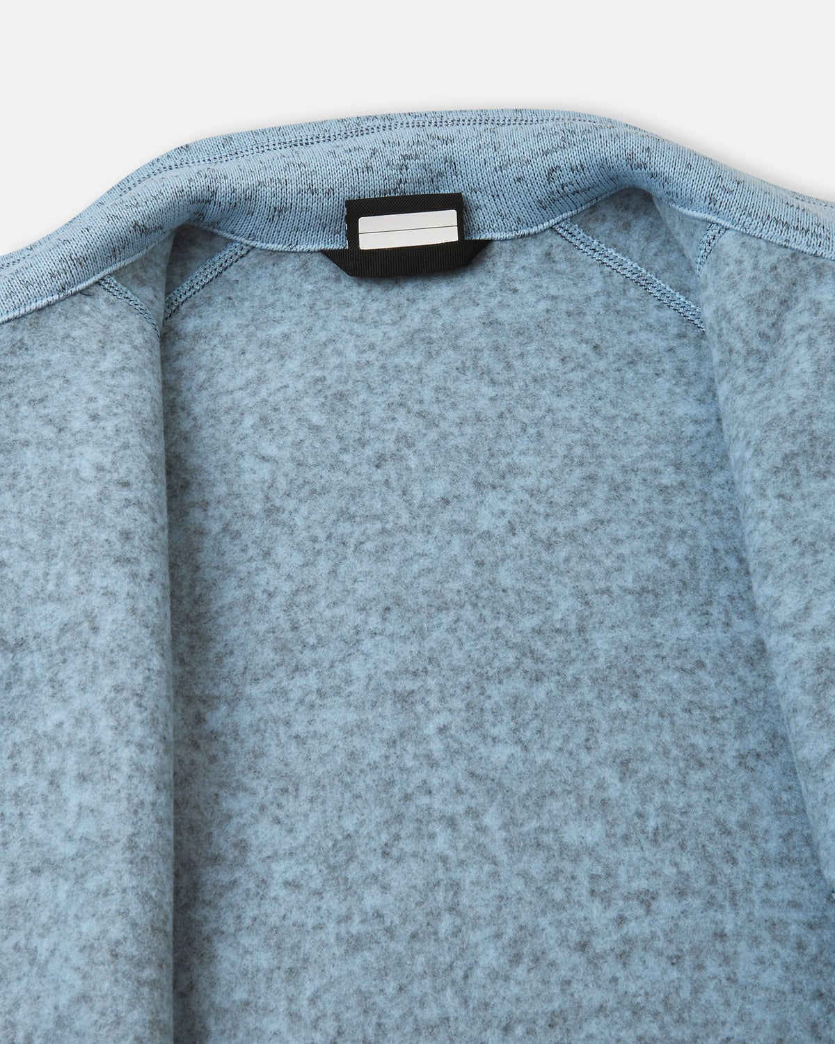 Detail view of the inner neck label on the frozen blue Reima Laskien kids' fleece jacket, featuring space for a name tag and highlighting the soft, warm fleece lining.