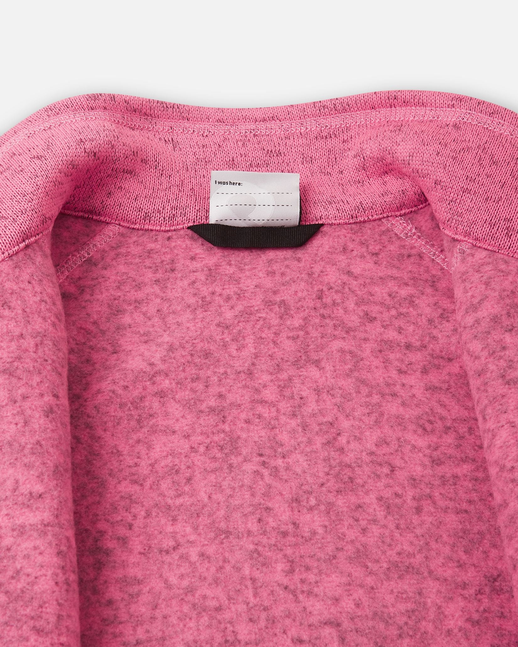 Detail view of the inner neck label on the soft coral Reima Laskien kids' fleece jacket, featuring space for a name tag and highlighting the soft, warm fleece lining.