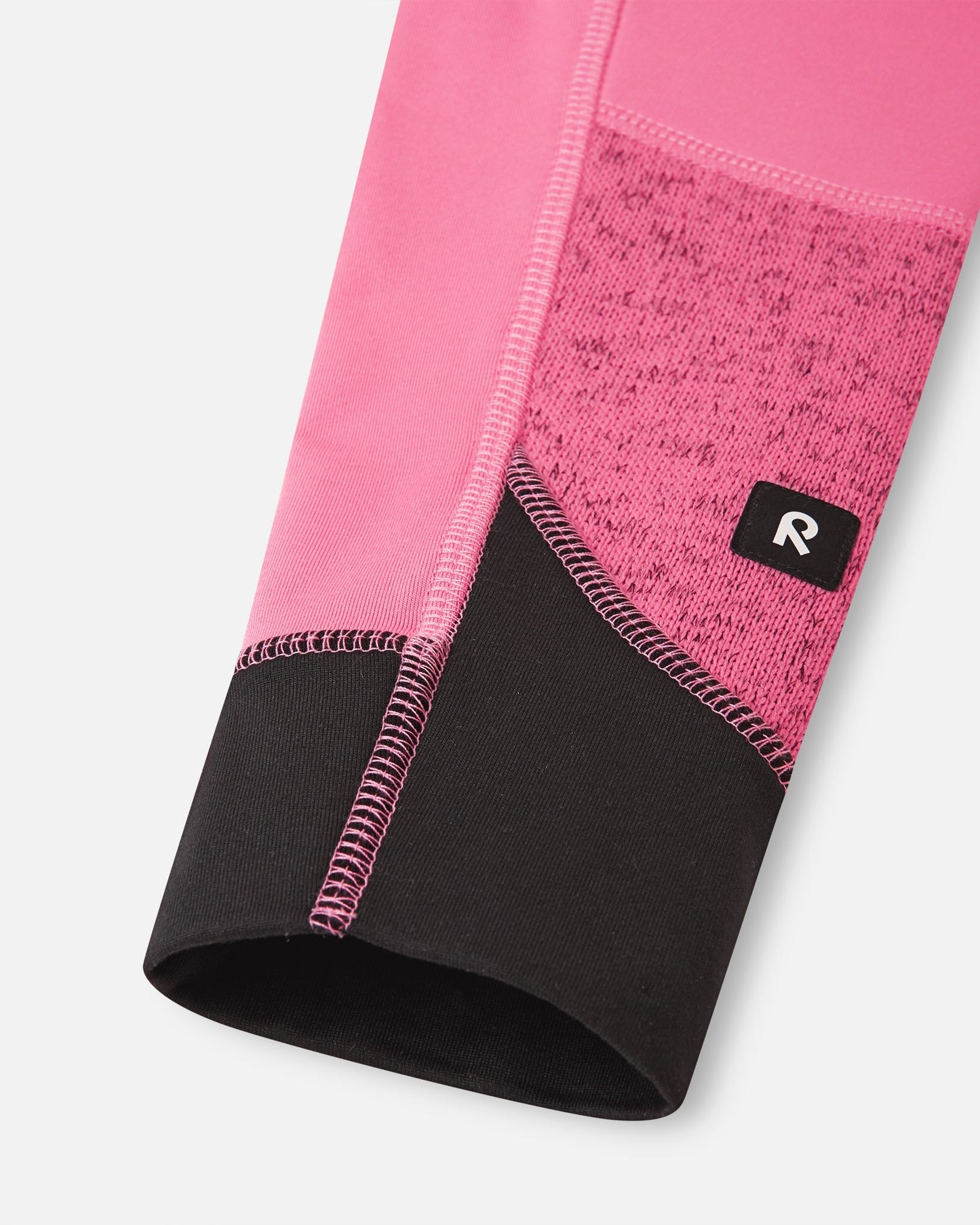 Detailed close-up of the reinforced black sleeve cuff on the soft coral Reima Laskien kids' fleece jacket, showing the high-quality stitching and branded Reima logo tab.