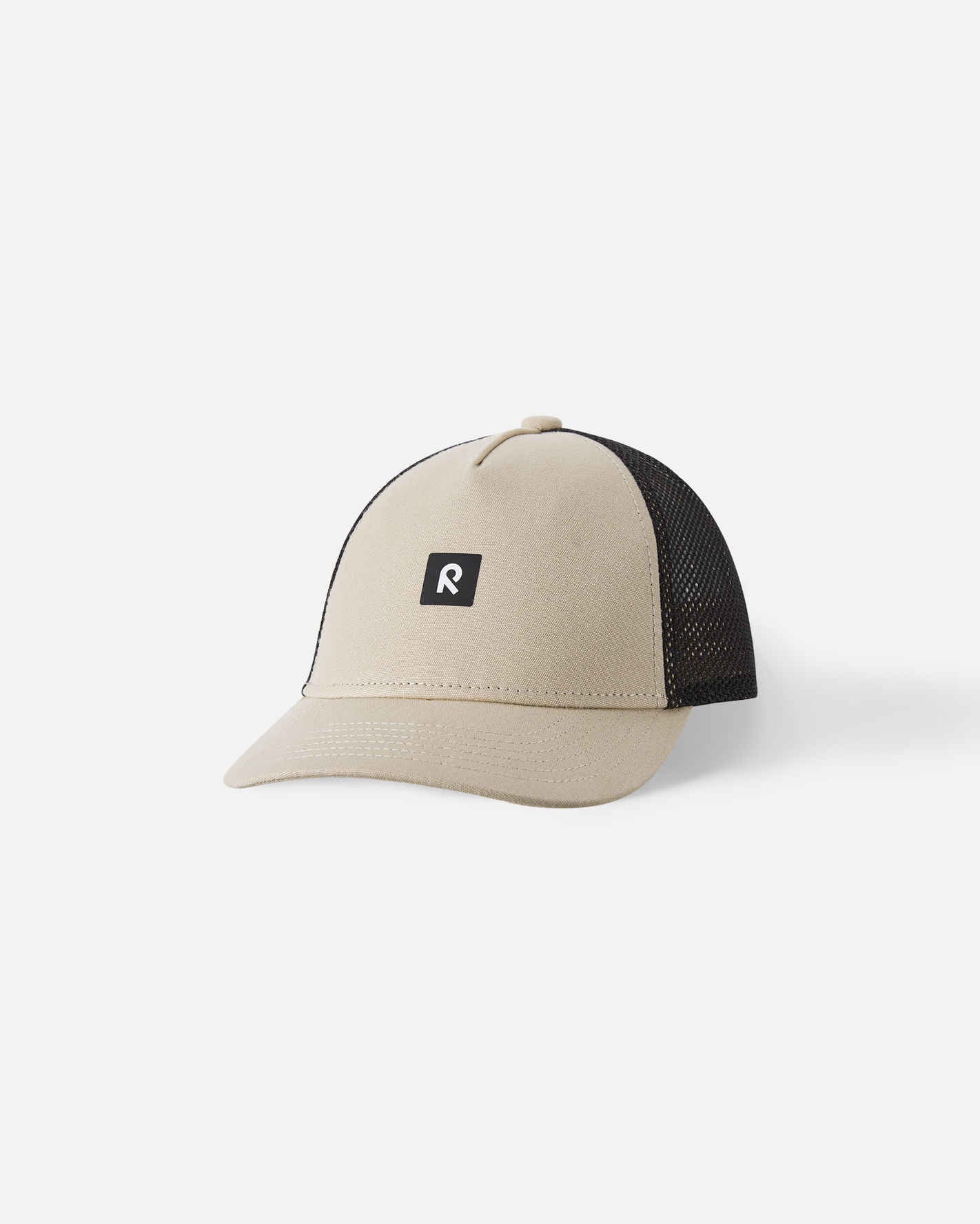 Front view of the Reima Liplatus kids' organic cotton cap in earthy beige, featuring a breathable black mesh back, a classic curved brim for sun protection, and a black Reima logo patch.