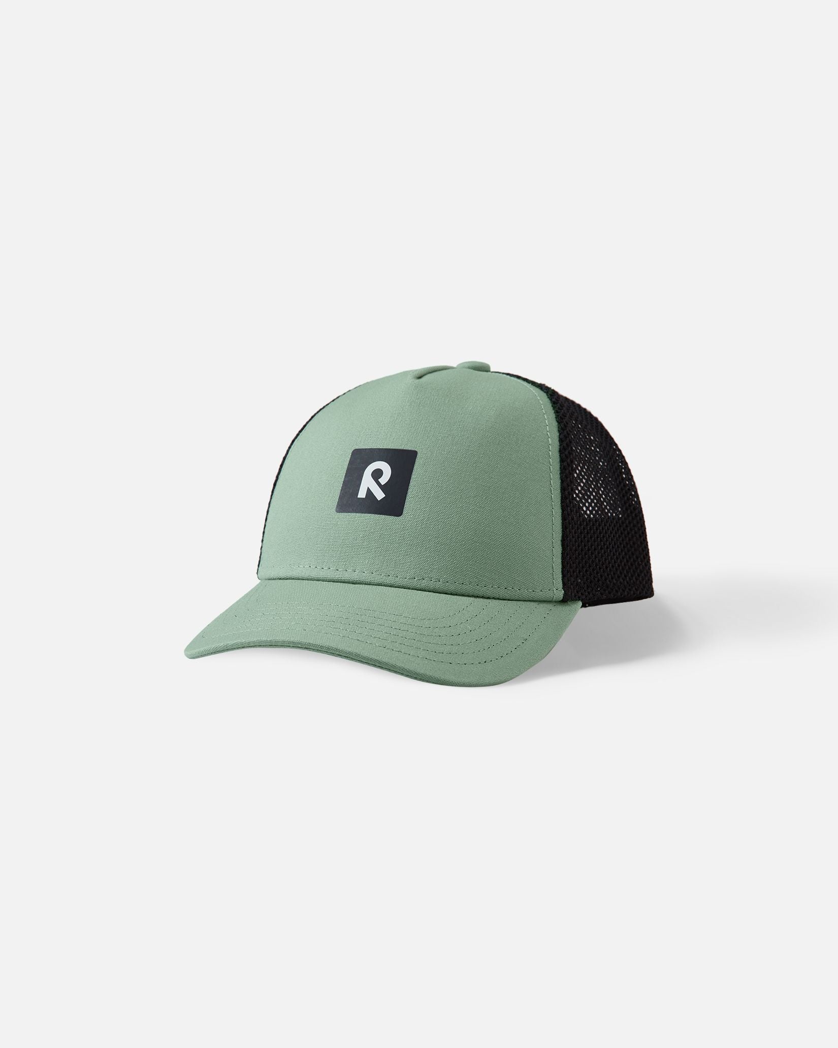 Front view of the Reima Liplatus kids' organic cotton cap in stone green, showcasing the durable pale green woven front panel, breathable black mesh back, and central Reima logo.