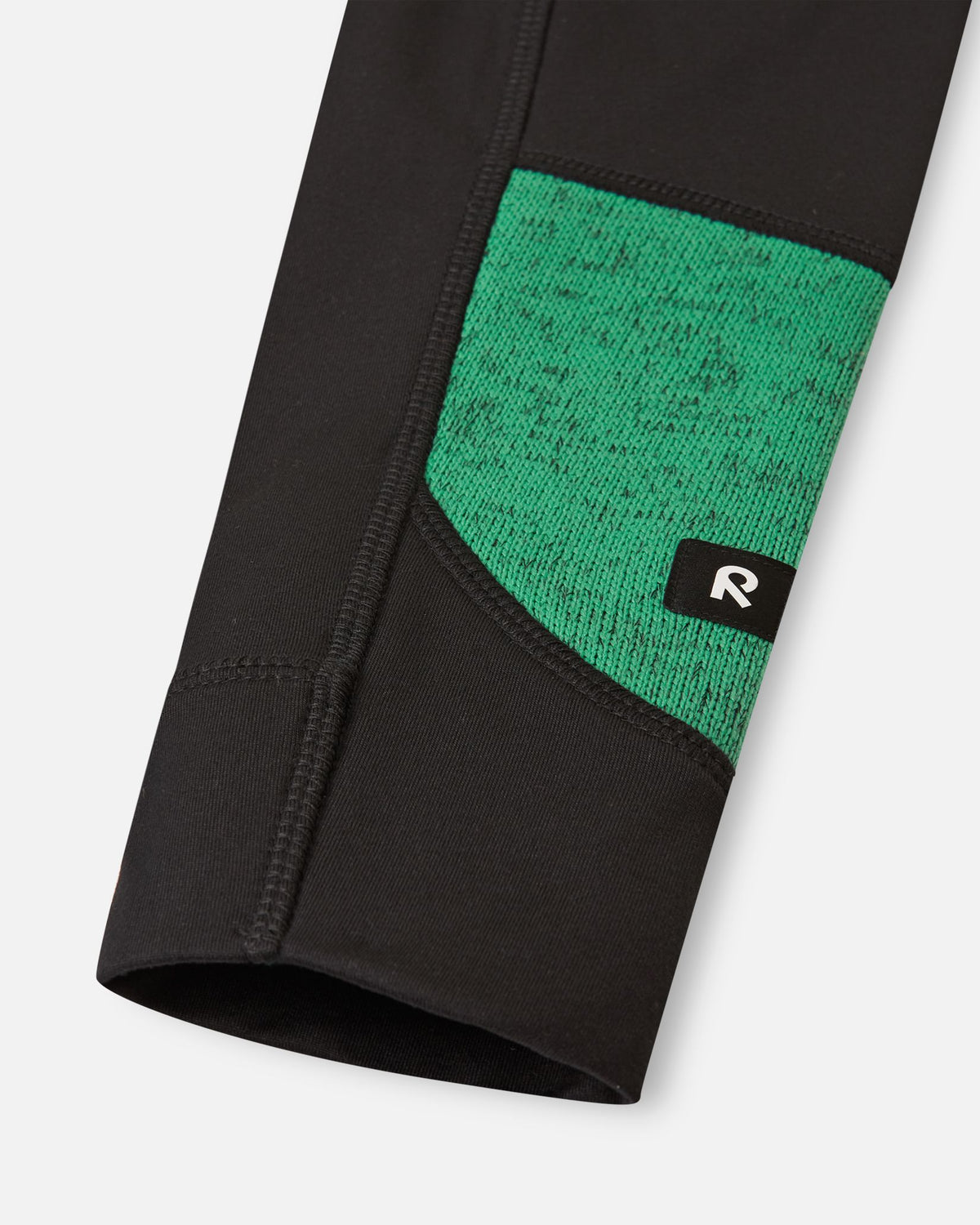 Close-up of the reinforced black sleeve cuff on the green Reima Liukuen kids' fleece jacket, showing durable stitching and the reflective Reima logo tab.