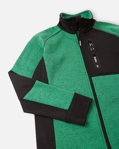 Detail of the secure zippered chest pocket on the green Reima Liukuen kids' fleece jacket, featuring a smooth zip pull and protective chin guard at the collar.