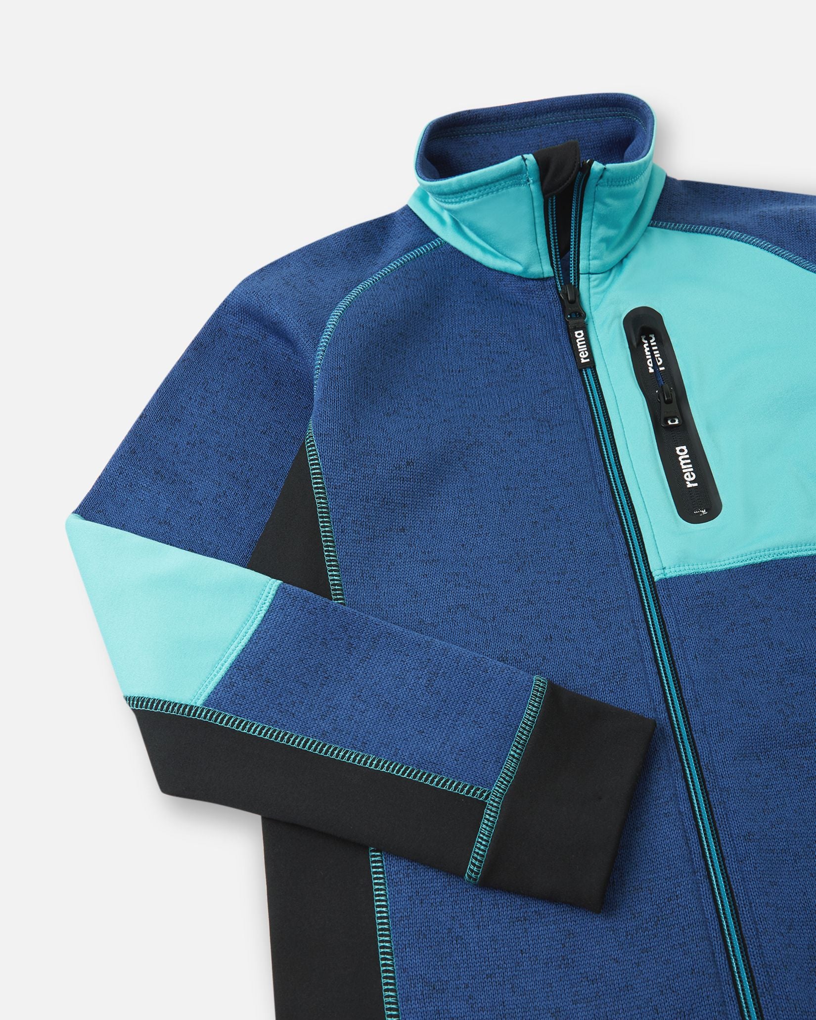 Close-up of the cyan blue zippered chest pocket on the twilight blue Reima Liukuen kids' fleece jacket, featuring a protective high collar and anti-chafe chin guard.