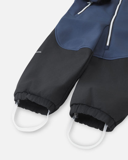 Detailed close-up of the gathered elastic ankle cuffs and durable silicone stirrup foot loops on the navy Reima Mjosa kids' softshell suit, designed to keep pant legs securely over boots.