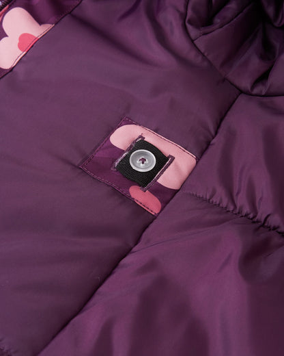 Close-up of the interior lining of the Reima Muurame girls' jacket, showing the internal button and elastic system that allows parents to cinch the waist for a tailored, snug fit.