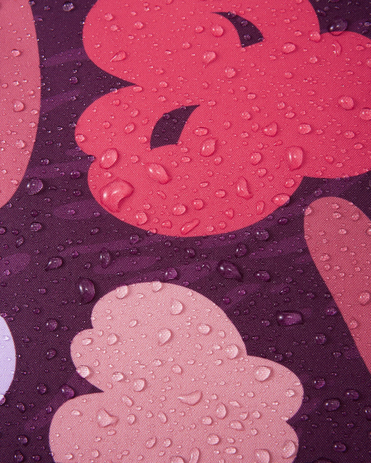 Macro close-up of water droplets tightly beading on the deep purple and pink Reimatec fabric of the Muurame jacket, demonstrating its excellent waterproof and weather-resistant performance.