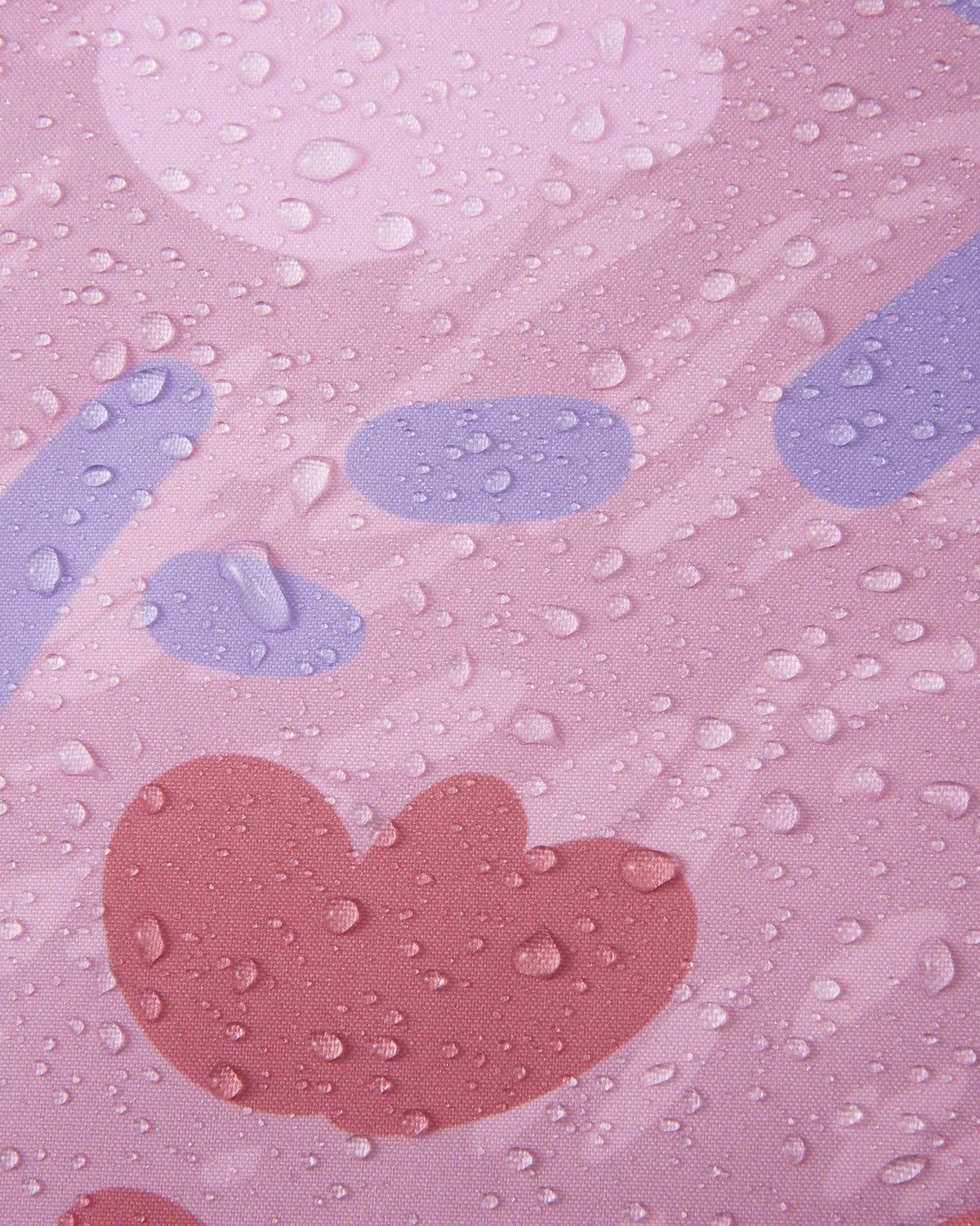 Macro close-up of water droplets tightly beading on the grey and pink patterned Reimatec fabric of the Muurame jacket, demonstrating its excellent waterproof and weather-resistant performance.