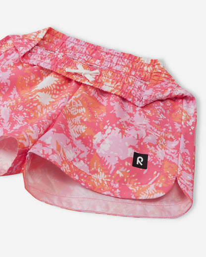 Close-up detail of the Reima Nauru girls' soft coral abstract swim shorts, focusing on the flexible gathered elastic waistband and the sturdy white inner drawstring that ensures the shorts stay secure.