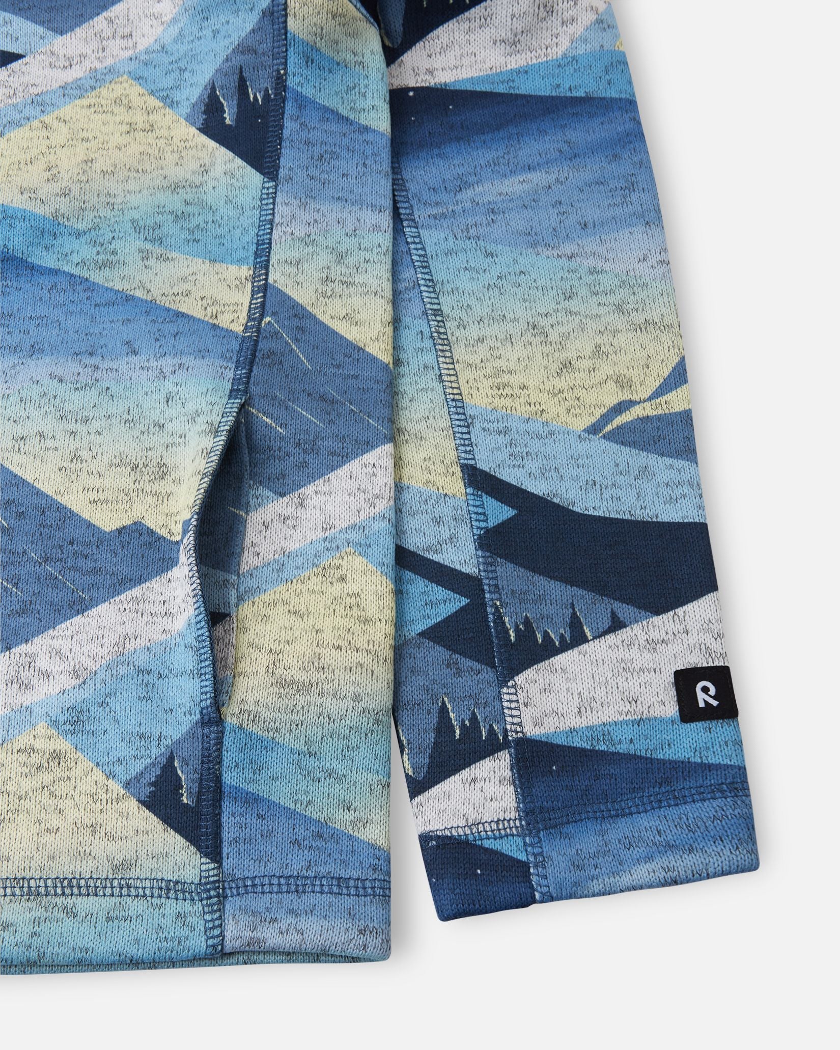 Close-up detail of the side pocket construction and sleeve cuff featuring the Reima logo tag on the blue ocean Reima Niksini kids' fleece jacket.