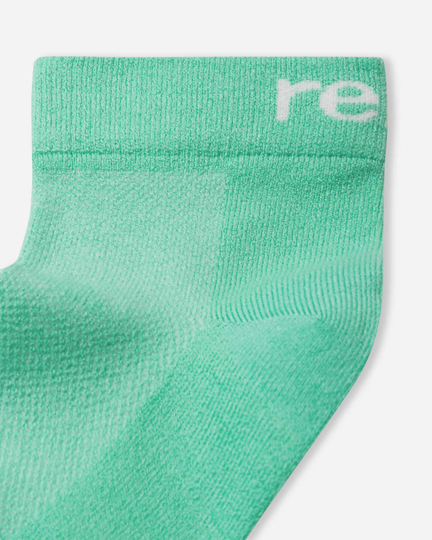 Flat lay view of the Reima Nilkat kids' ankle socks 2-pack, featuring one pair in a vibrant fresh mint green and one pair in classic white, crafted from a breathable cotton blend.