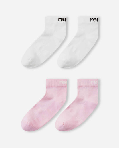 Flat lay view of the Reima Nilkat kids' ankle socks 2-pack, showcasing one pair in a soft light heather pink and one pair in solid white, offering a comfortable and secure fit for active children.