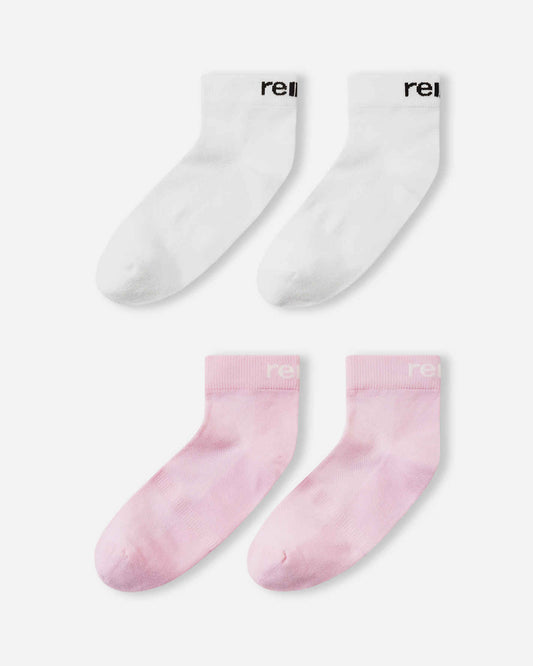 Flat lay view of the Reima Nilkat kids' ankle socks 2-pack, showcasing one pair in a soft light heather pink and one pair in solid white, offering a comfortable and secure fit for active children.