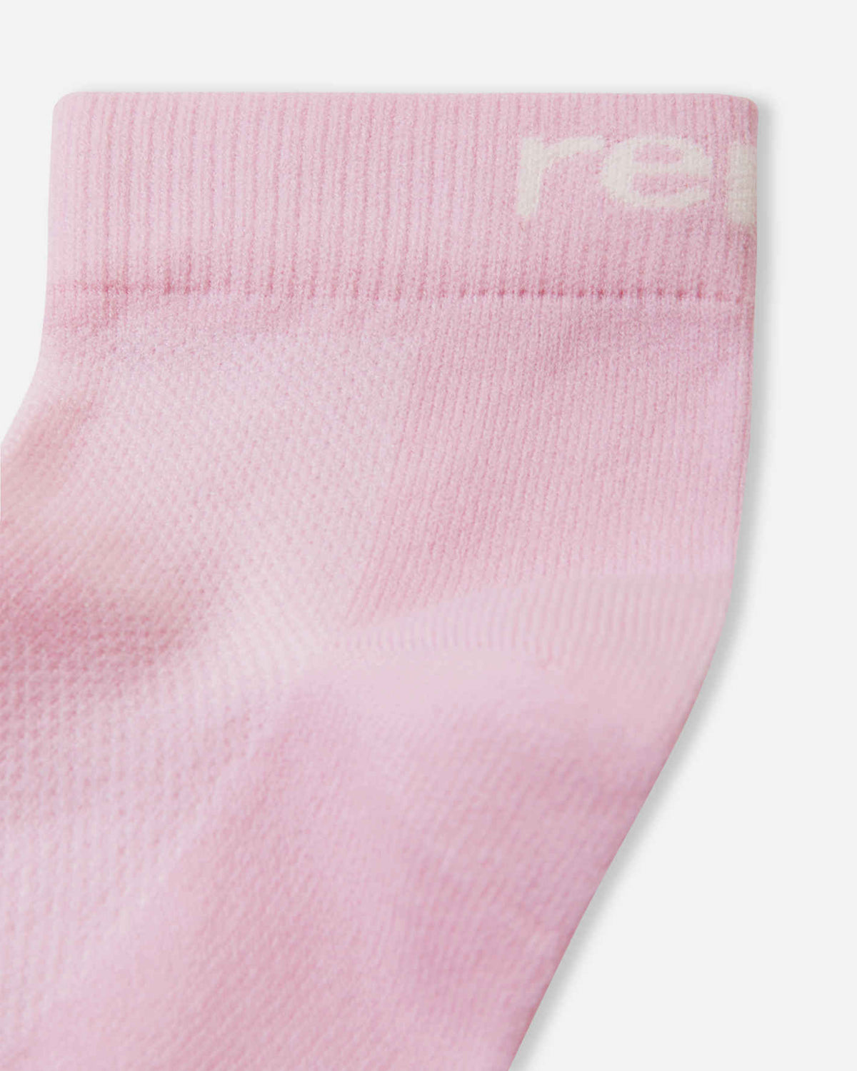 Detailed close-up of the Reima Nilkat kids' light heather pink ankle sock, focusing on the soft, stretchy knit texture, reinforced heel, and the subtle white Reima logo on the ribbed cuff.