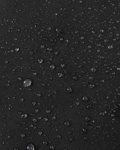 Macro close-up of water droplets beading tightly on the black Reimatec waterproof fabric of the Reima Ote kids' winter mittens, demonstrating superior snow and moisture resistance.