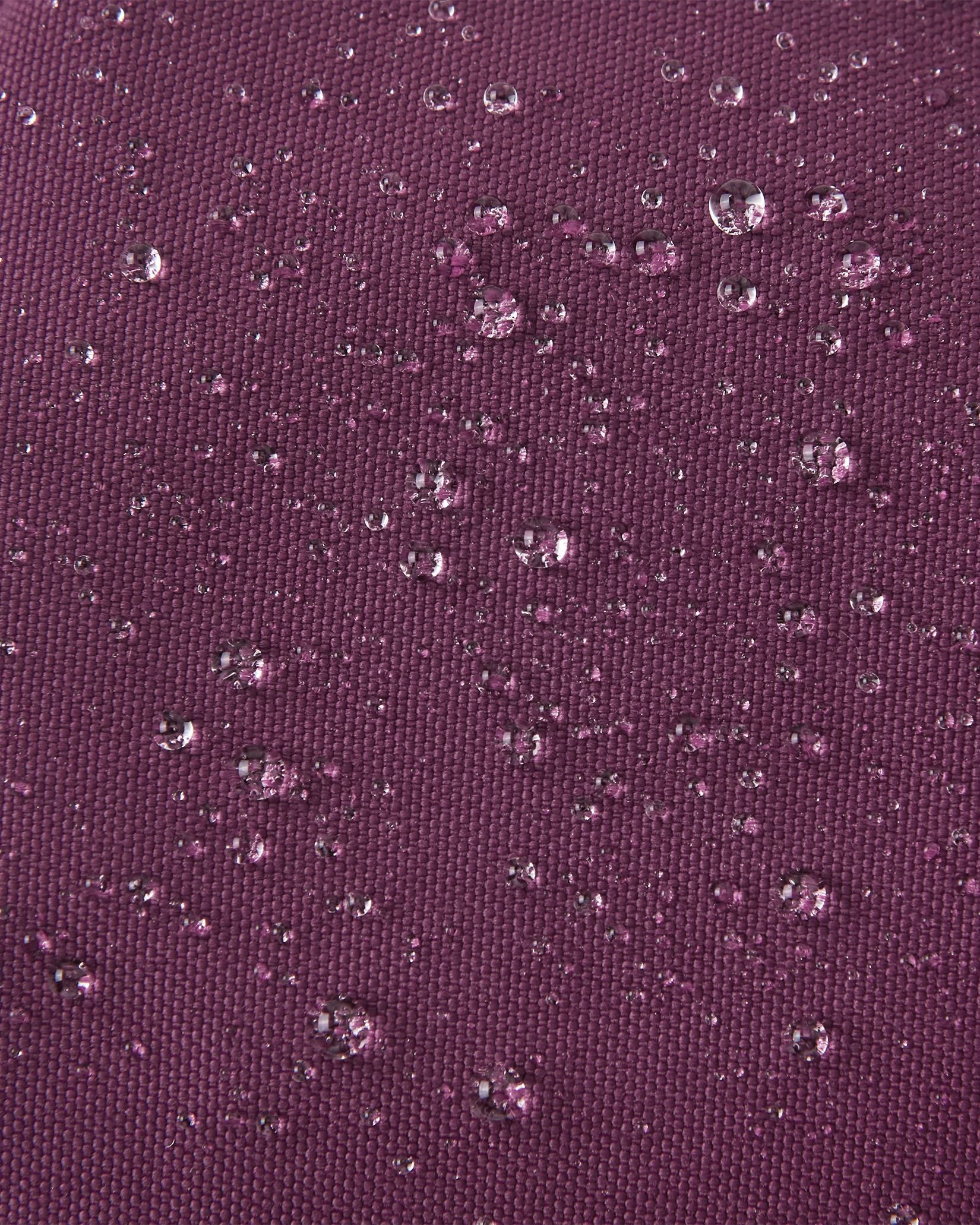 Macro close-up showing water perfectly beading off the deep purple waterproof Reimatec exterior of the Reima Ote kids' winter mittens, highlighting their advanced rain and snow resistance.