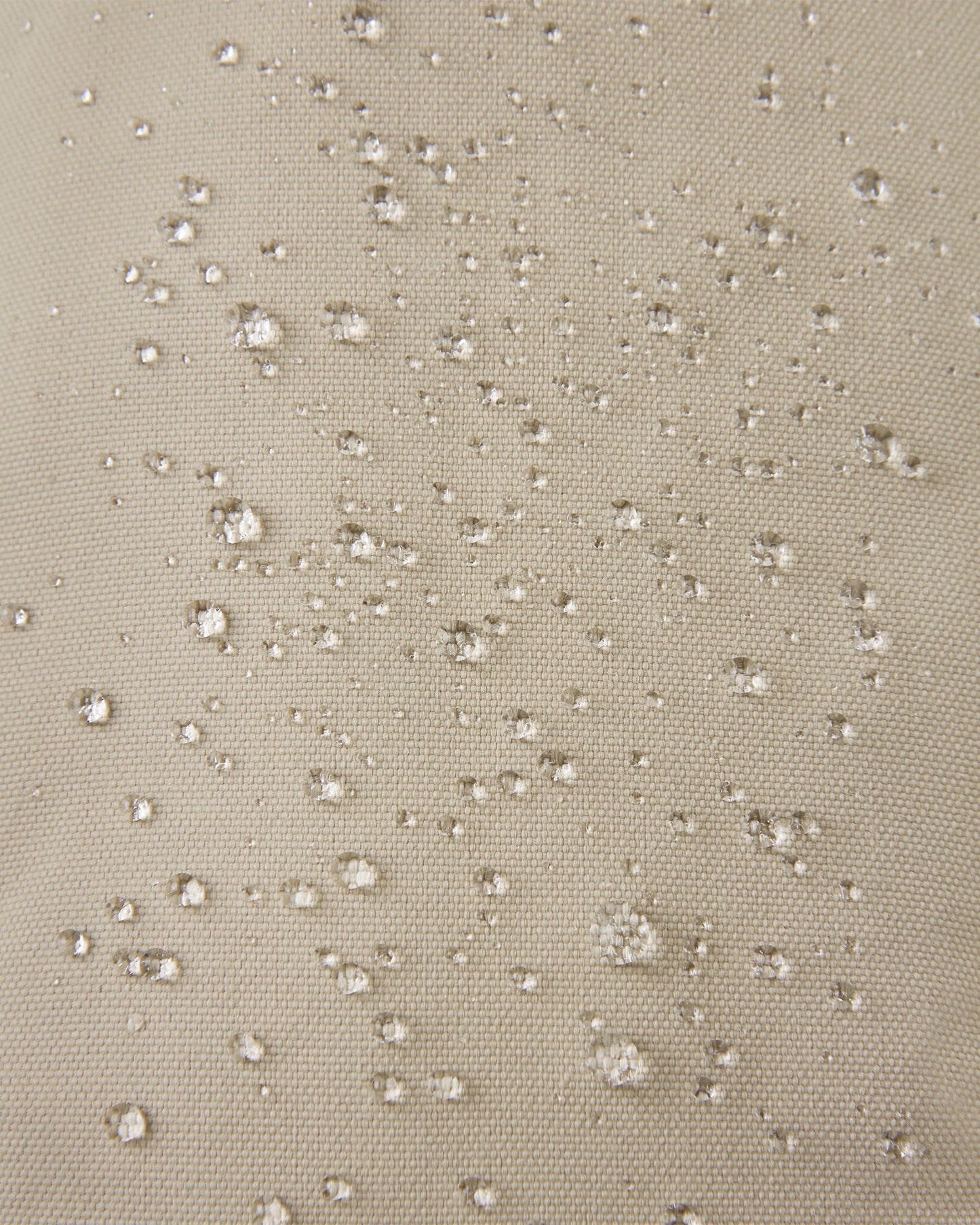 Macro close-up showing water perfectly beading off the earthy beige waterproof Reimatec exterior of the Reima Ote kids' winter mittens, demonstrating advanced rain and snow resistance.